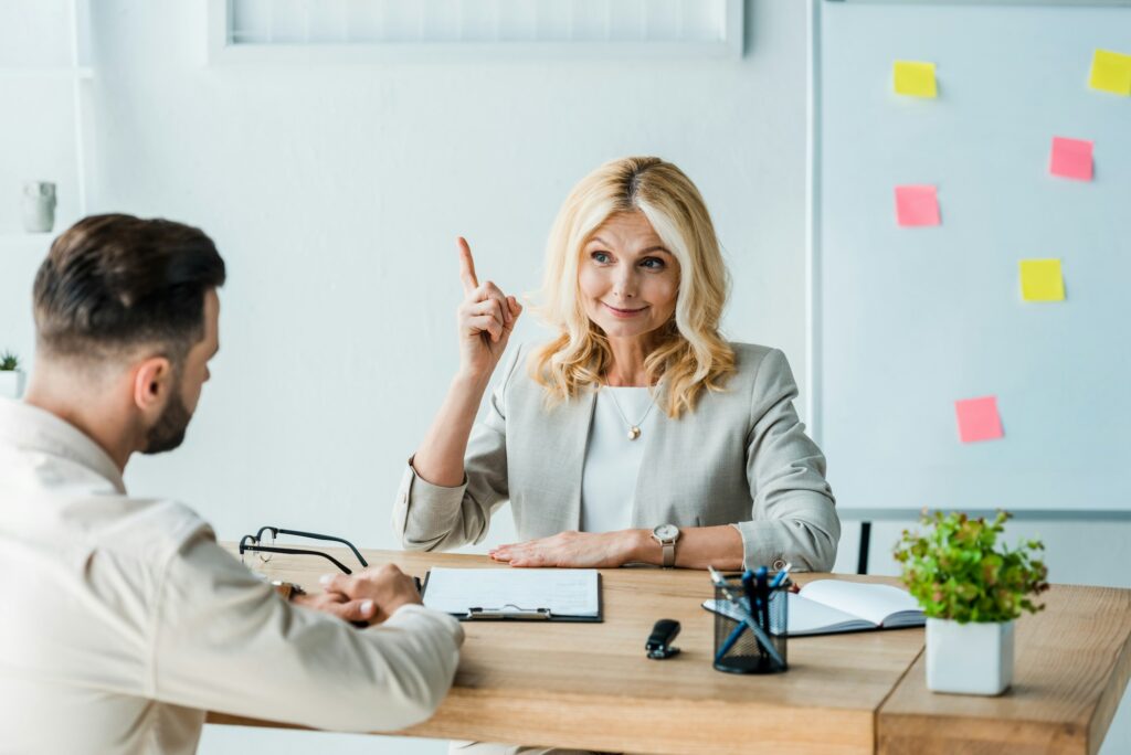 selective focus of happy recruiter gesturing near employee in office