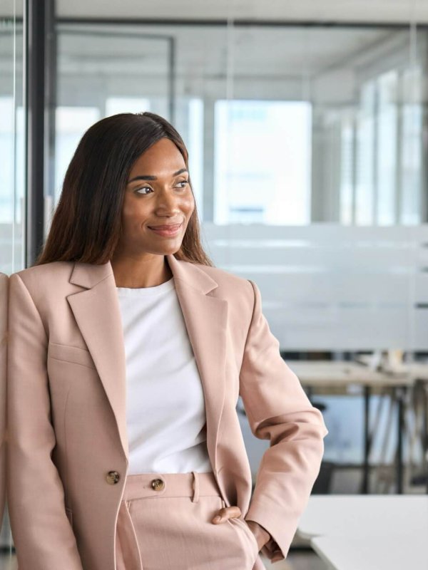 Confident young business woman standing in office looking away, portrait.
