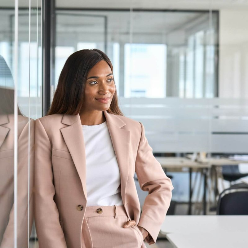Confident young business woman standing in office looking away, portrait.