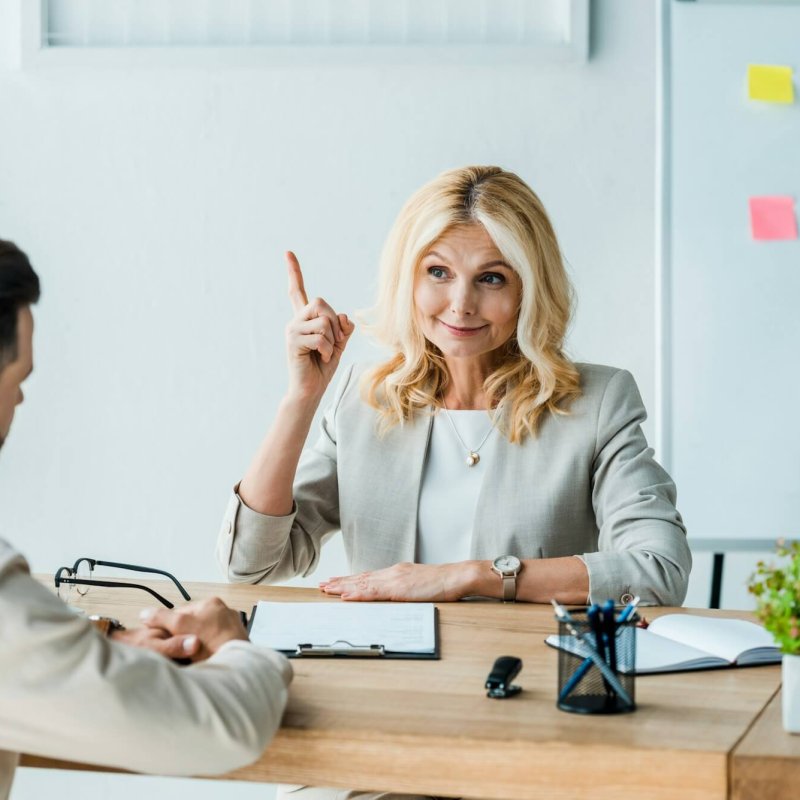 selective focus of happy recruiter gesturing near employee in office