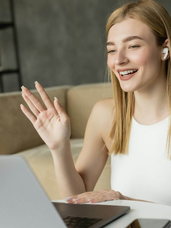 Smiling blonde coach in earphone having video call on laptop at home